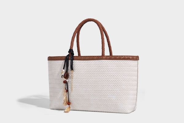 Structured woven-texture tote bag with brown braided top handles, decorative tassel charm, and detachable shoulder strap
