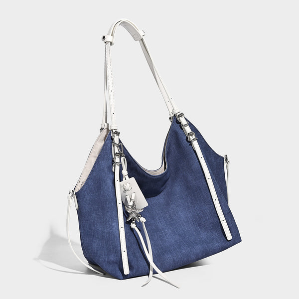 Große, lässige Schultertasche im Shopper-Stil aus Canvas in Denim-Optik mit weißen Trägern in Lederoptik, silberfarbenen Schnallendetails und hängendem