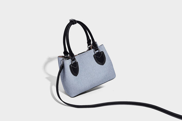 Structured light-blue denim-look tote bag with black leather-look handles, white contrast stitching, silver-tone hardware