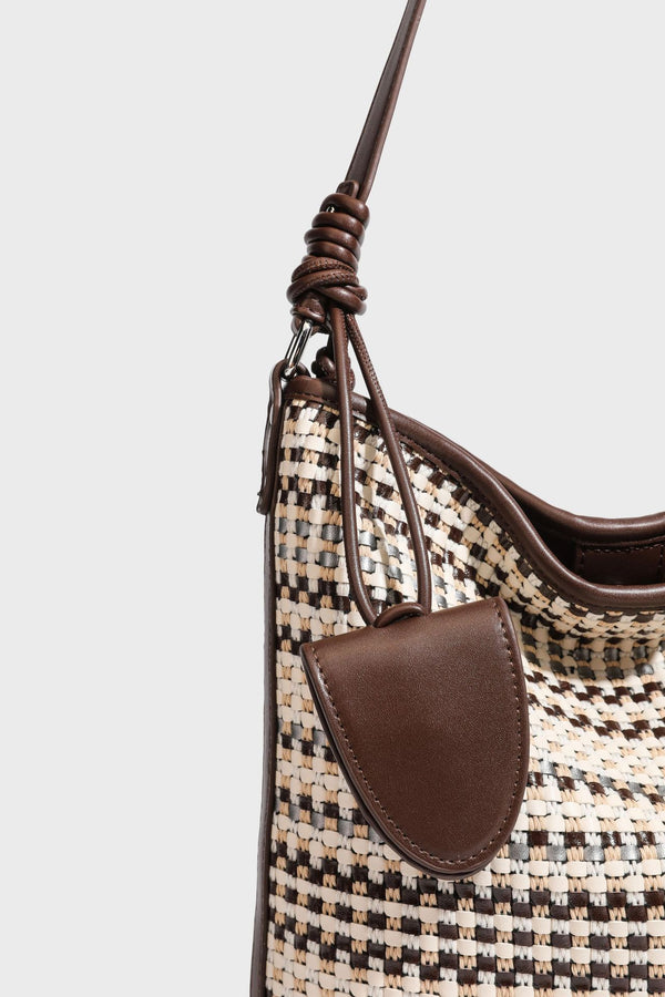 Woven stripe bucket shoulder bag in cream and dark brown with leather-look trim, knotted adjustable strap, and small shield