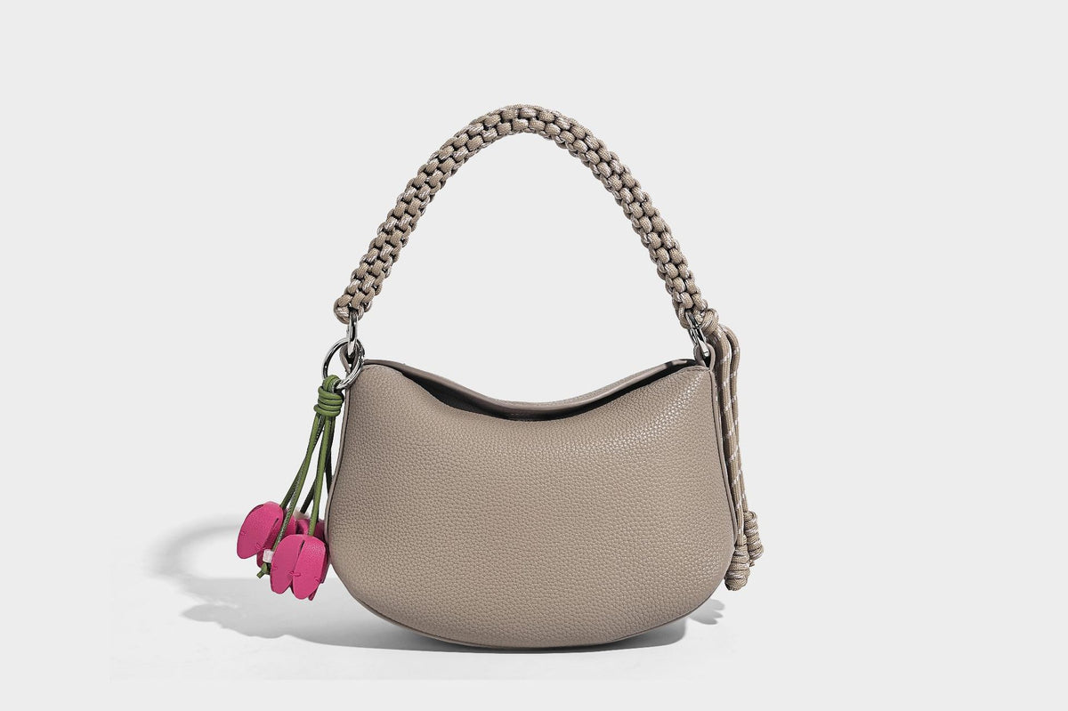 Small crescent half-moon bag in pebbled leather-look finish with braided top handle, silver-tone ring hardware, and, detail