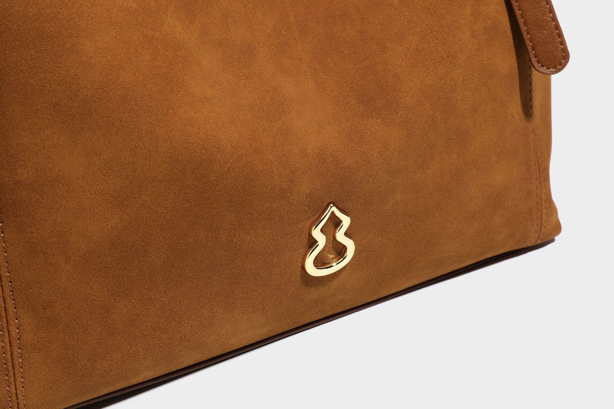 Oversized suede-finish tote shoulder bag in caramel brown with slim leather-look straps and gold-tone logo hardware, detail
