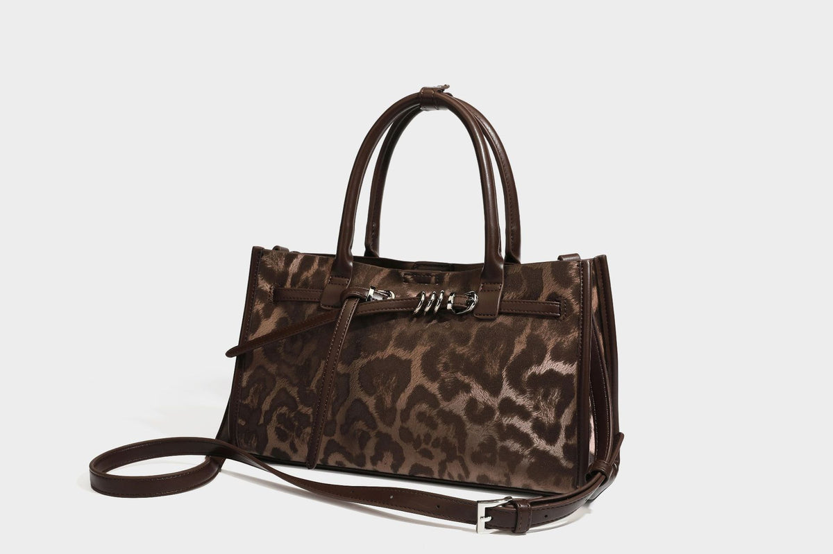 Structured leopard-print tote bag with glossy satin-like finish, dual rounded top handles, silver buckle-and-ring front