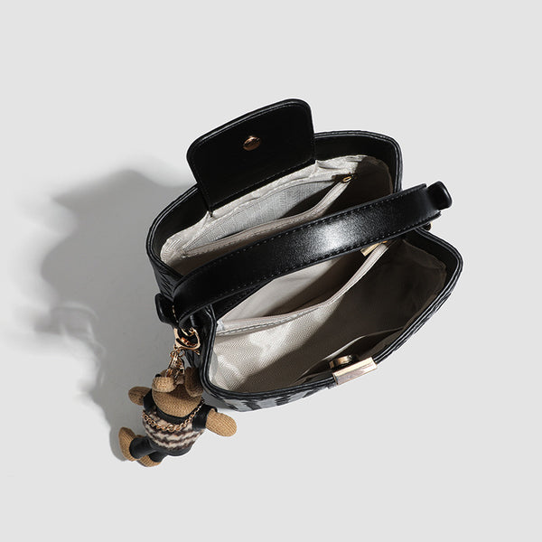 Black woven leather-look bucket bag with gold-tone clip closure, top handle, detachable shoulder strap, and knit bunny charm
