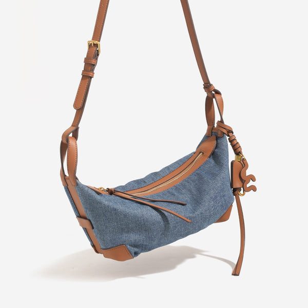 Washed denim canvas crescent hobo bag with tan leather-look trim, knotted strap detail, and gold-tone zipper hardware, detail