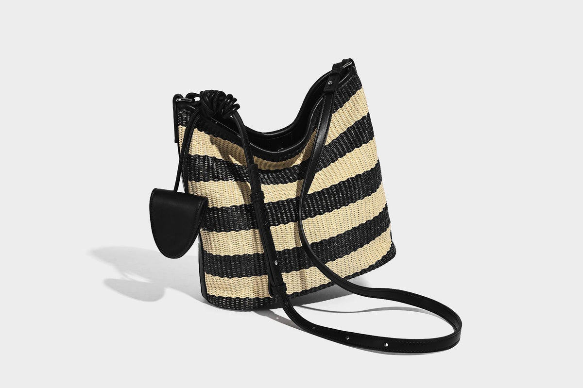 Gestreifte gewebte Bucket Bag in Schwarz und Beige mit schwarzem Besatz in Lederoptik, offener Oberseite und langem verstellbarem Schulterriemen, Detailansicht