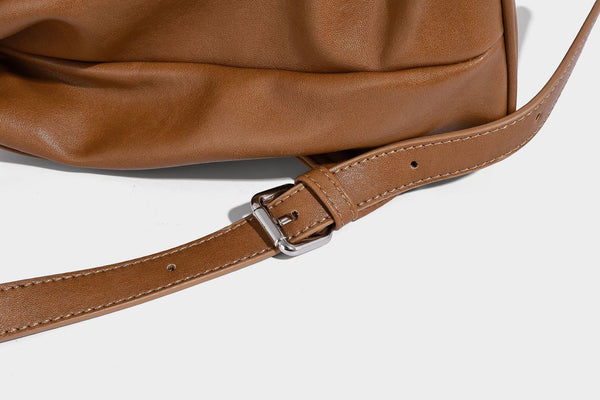 Structured tan leather-look flap backpack handbag with top handle, silver buckle hardware, and fold-over front closure