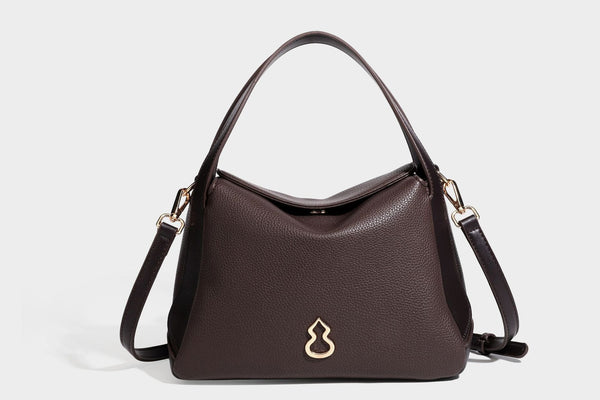 Structured pebbled leather-look shoulder bag with flap top, gold-tone emblem hardware, dual top handles, and detachable