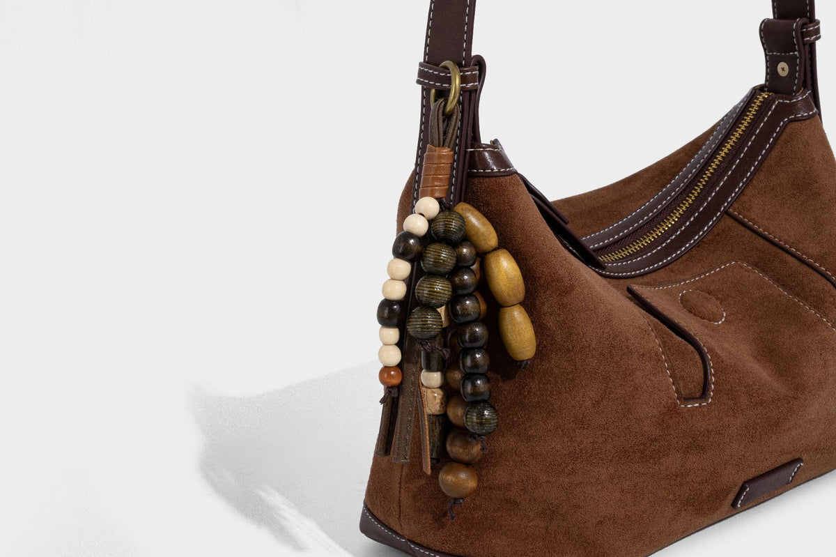 Matte Hobo-Schultertasche in warmem Braun mit dunklem Besatz in Lederoptik, Kontrastnähten, goldfarbenen Metallbeschlägen und