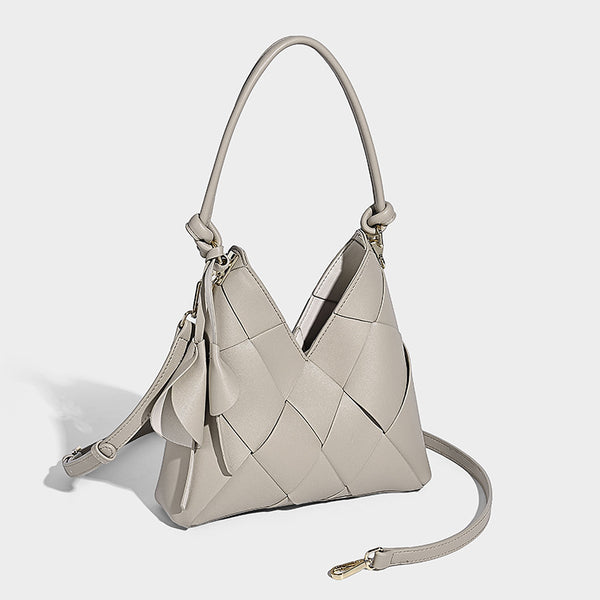 Compact bucket shoulder bag with black-and-white diamond patchwork panels, knotted top handle, gold-tone hardware, and
