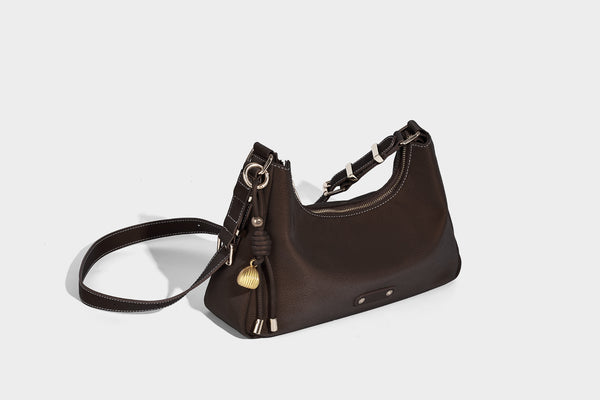 Crescent hobo shoulder bag in pebbled leather-look finish with top zipper, adjustable strap, gold-tone ring hardware, and