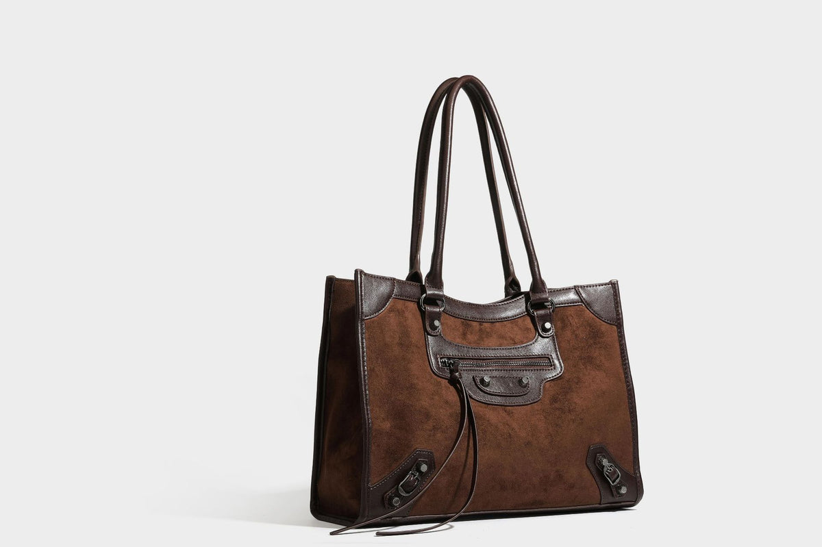 Large structured tote bag with matte suede-like body, smooth leather-look trim, front zip pocket, stud hardware, and