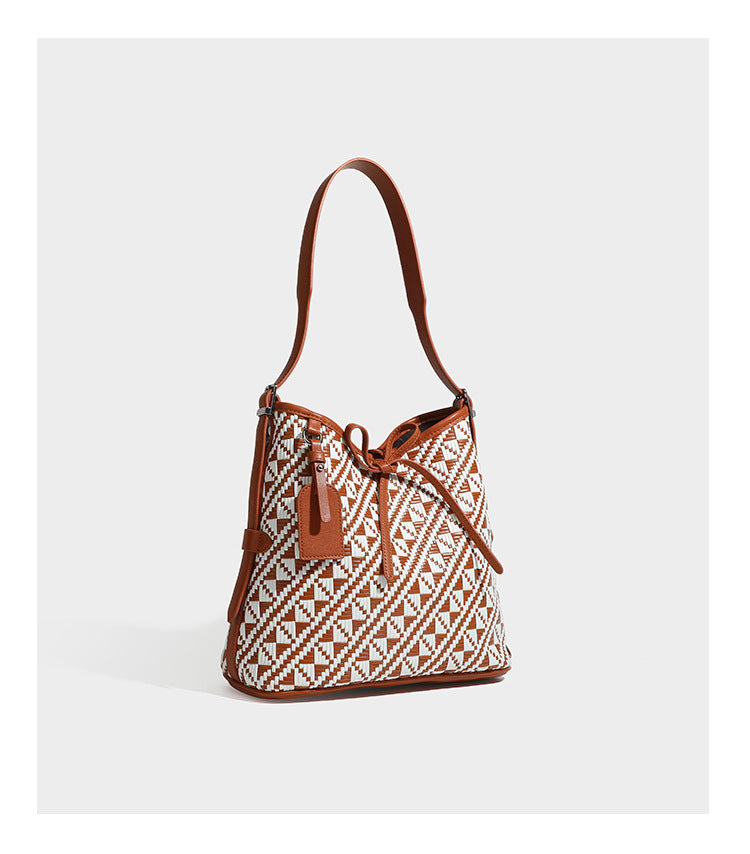 Woven geometric bucket shoulder bag in white and dark brown two-tone pattern with leather-look trim and drawstring top