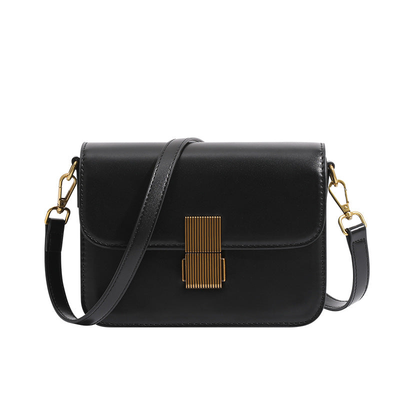 Mini structured black flap crossbody bag with gold-tone ribbed rectangular clasp and adjustable shoulder strap, detail view 5