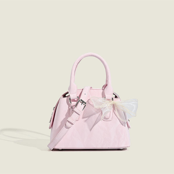 Small structured Boston bag in cream with glossy crinkled finish, sheer bow accent, silver-tone hardware, dual top handles