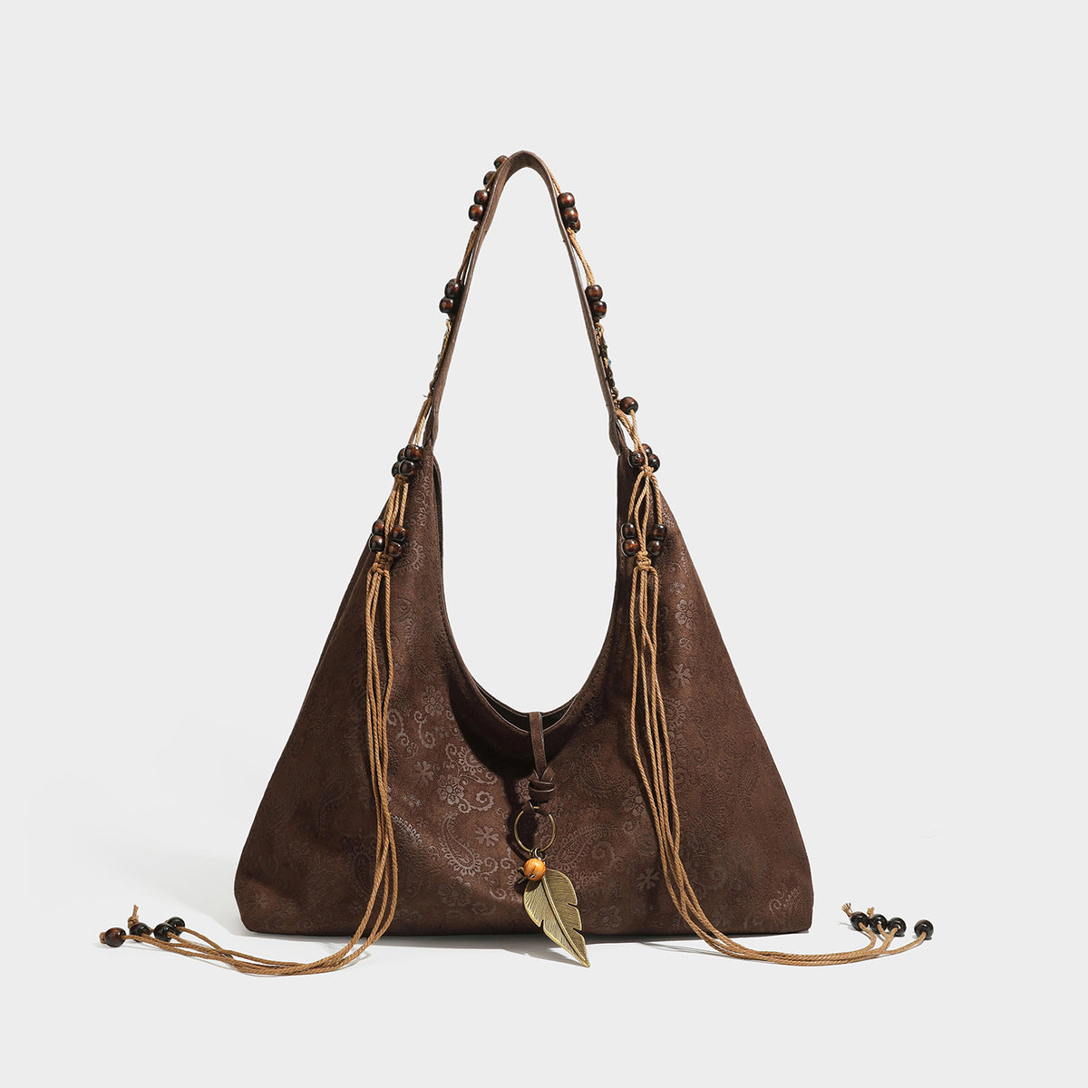 Slouchy boho hobo shoulder bag in embossed brown suede-look finish with beaded strap, cord tassels, and brass-tone leaf