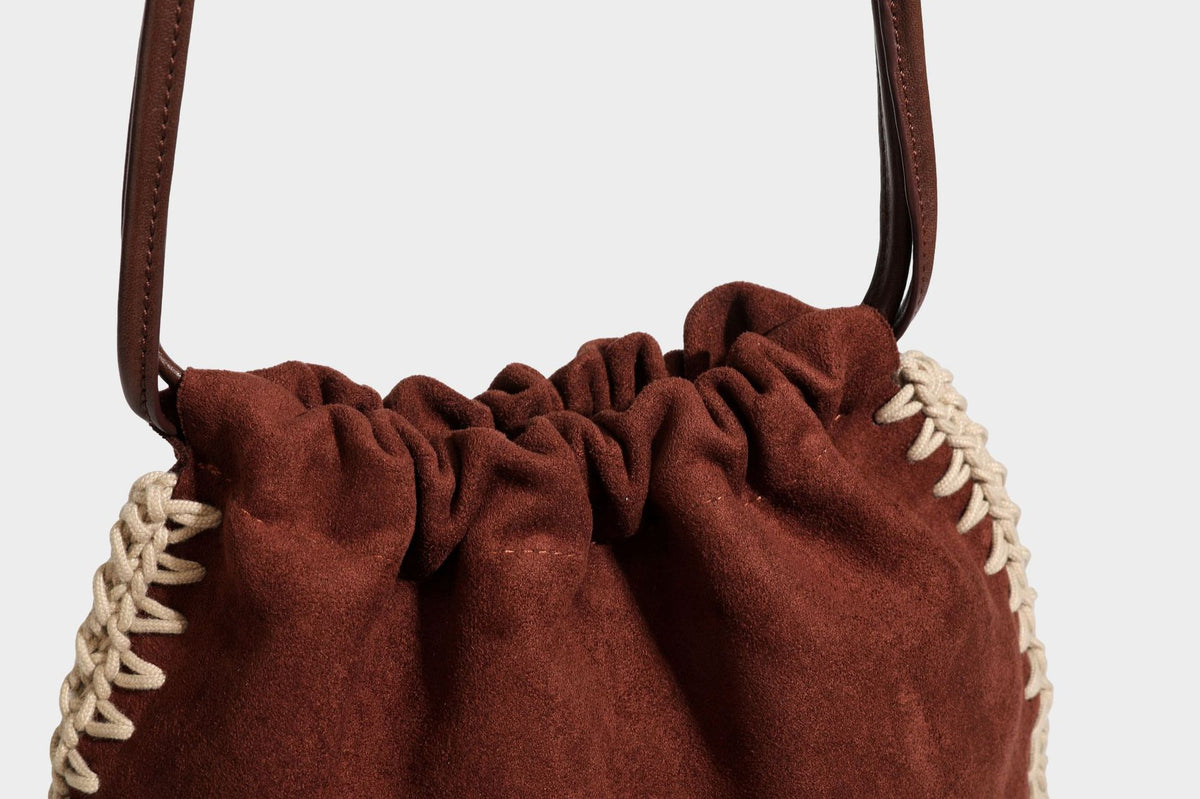 Matte suede-look drawstring bucket bag with cream braided woven edge trim and slim adjustable leather-look shoulder strap