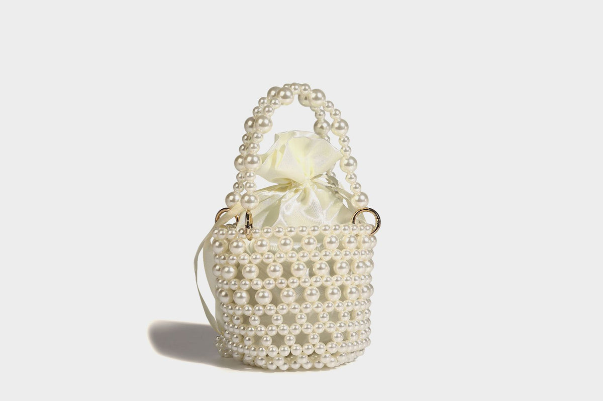 Elfenbeinfarbene Mini-Bucket-Bag aus Kunstperlen mit Satin-Innenbereich und Zugband, goldfarbenen Ringbeschlägen und gewölbtem Perlenhenkel an der Oberseite