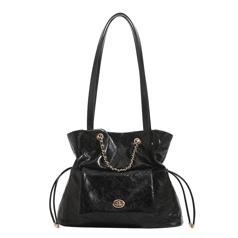 Black glossy diamond-quilted bucket tote bag with gold-tone chain accent, turn-lock front flap pocket, drawstring side ties