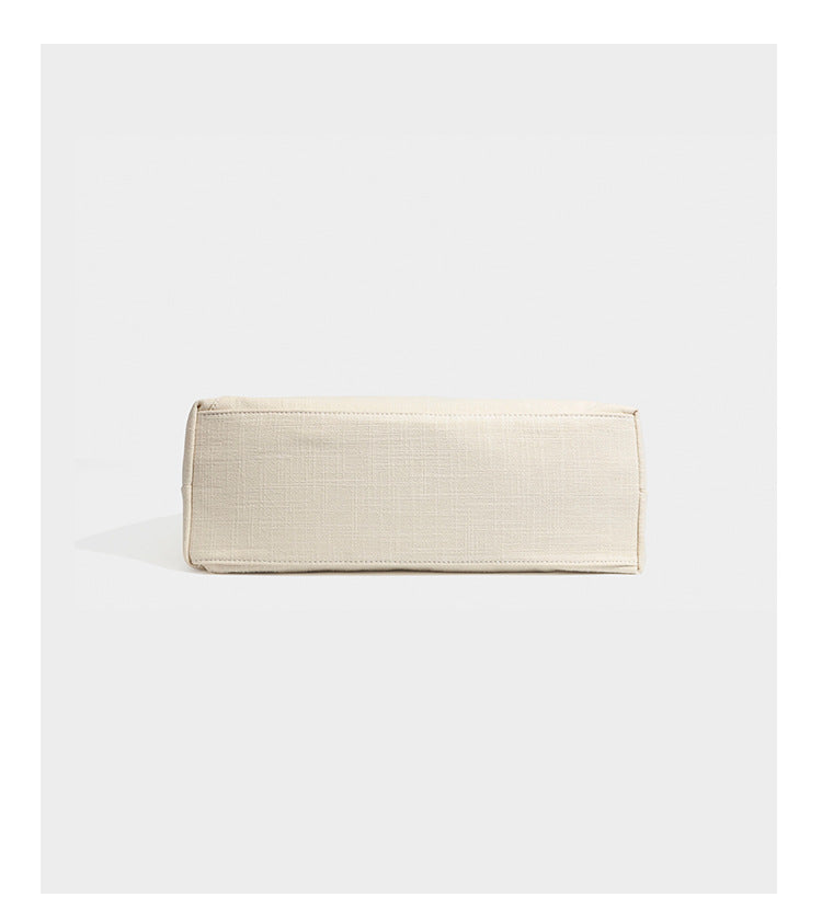 Soft slouchy cream canvas shoulder tote with braided brown and green cord handle, gold-tone ring hardware, and tassel trim