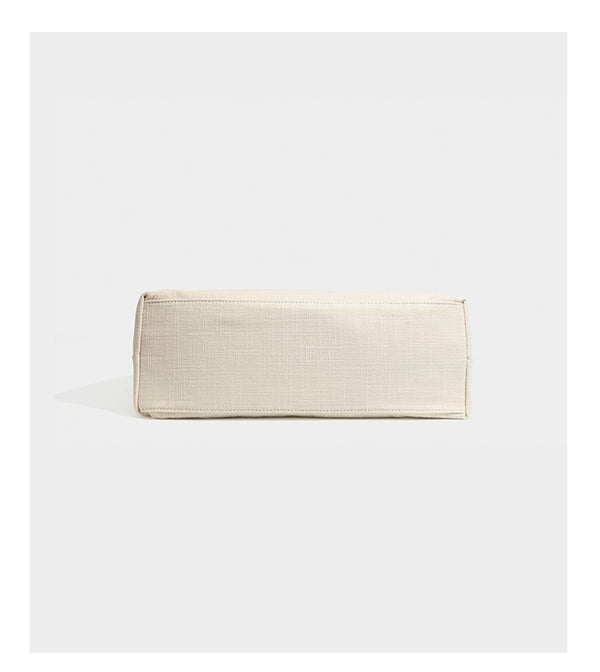 Soft slouchy cream canvas shoulder tote with braided brown and green cord handle, gold-tone ring hardware, and tassel trim