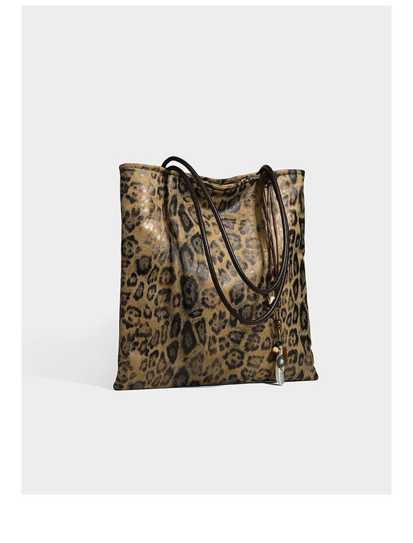 Large leopard print shoulder tote bag in tan and brown with slim dark straps and dangling beaded charm hardware, detail view