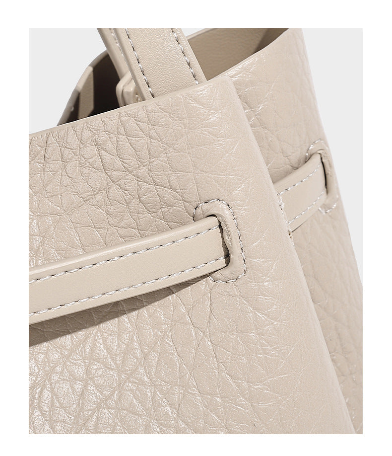 Small structured pebbled bucket tote with double top handles, silver turn-lock hardware, and detachable shoulder strap
