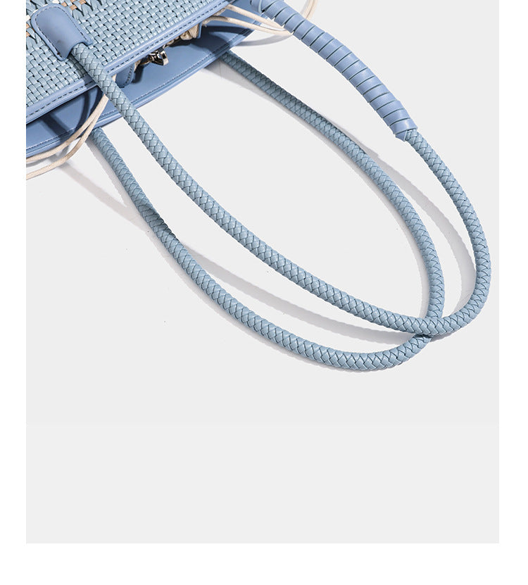 Light blue open-weave woven bucket tote bag with long braided shoulder straps, drawstring side ties, and attached mini pouch