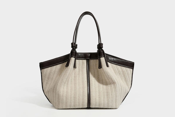 Cremefarbene geflochtene Tote-Bag mit dunkelbraunen Besätzen in Lederoptik, kontrastierenden weißen Nähten, zwei oberen Henkeln und abnehmbarem Schulter