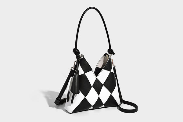 Compact bucket shoulder bag with black-and-white diamond patchwork panels, knotted top handle, gold-tone hardware, and