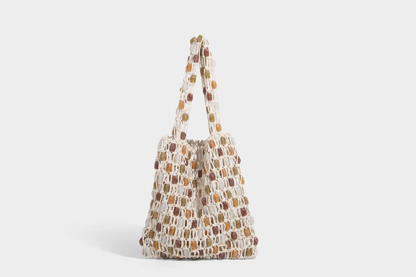 Cream macramé open-weave tote bag with multicolor amber olive and translucent bead accents and woven shoulder straps, detail