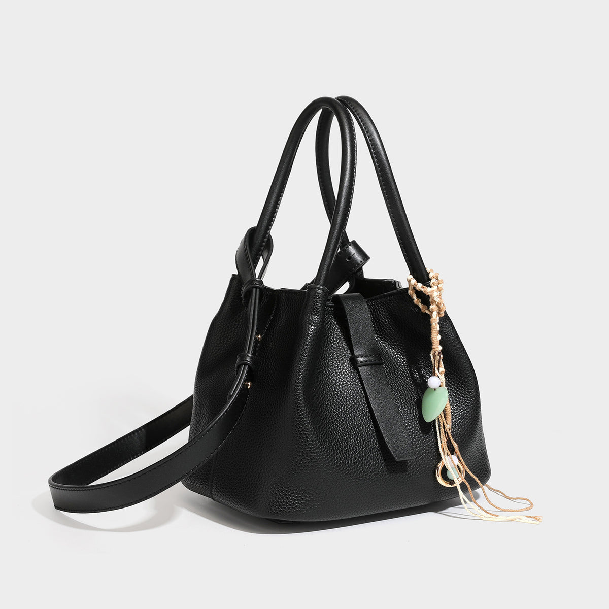 Pebbled leather-look bucket tote bag with rolled double handles, drawstring closure, braided cord charm, and detachable