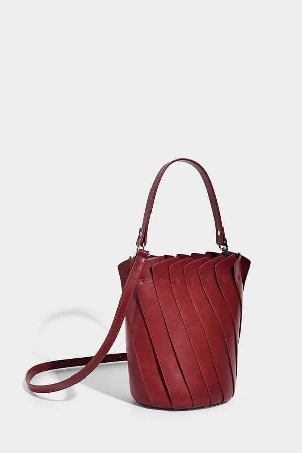 Structured pleated-panel bucket bag with curved top handle and detachable adjustable shoulder strap in smooth matte, detail