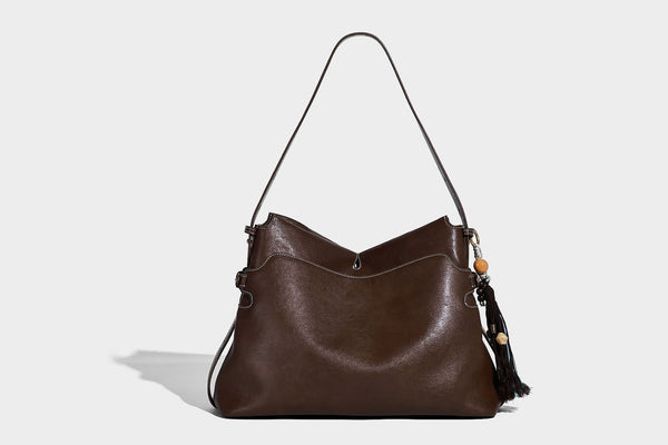 Large slouchy leather-look hobo tote bag with open top, adjustable shoulder strap, and colorful tassel bead charm, detail