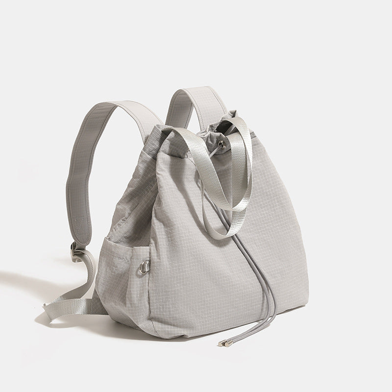 Glacier gray grid-texture nylon drawstring bucket convertible backpack with top handles and adjustable shoulder straps, front