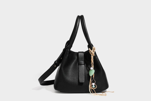 Pebbled leather-look bucket tote bag with rolled double handles, drawstring closure, braided cord charm, and detachable
