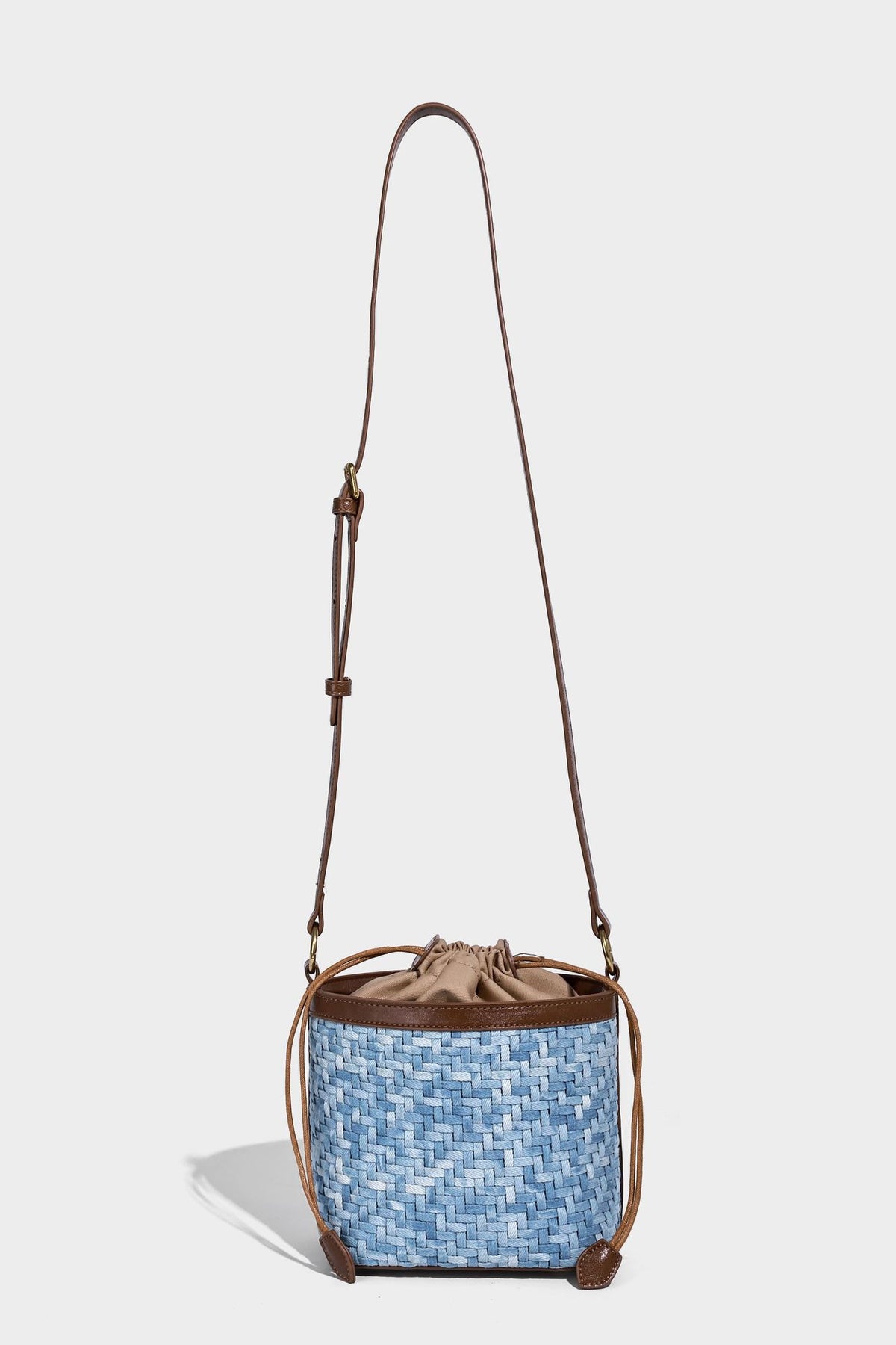 Small light blue woven bucket bag with brown leather-look trim, braided top handle, brass-tone ring hardware, drawstring
