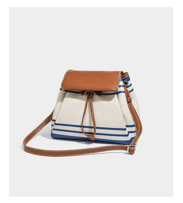 Cream canvas bucket bag with blue horizontal stripes, tan leather-look flap and trim, drawstring closure, silver-tone, detail