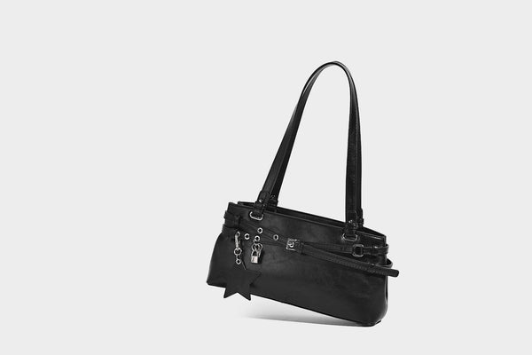 Structured glossy leather-look shoulder bag with wraparound belt straps, silver-tone hardware, and dangling star charm