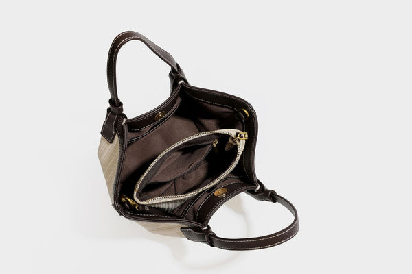 Cremefarbene geflochtene Tote-Bag mit dunkelbraunen Besätzen in Lederoptik, kontrastierenden weißen Nähten, zwei oberen Henkeln und abnehmbarem Schulter
