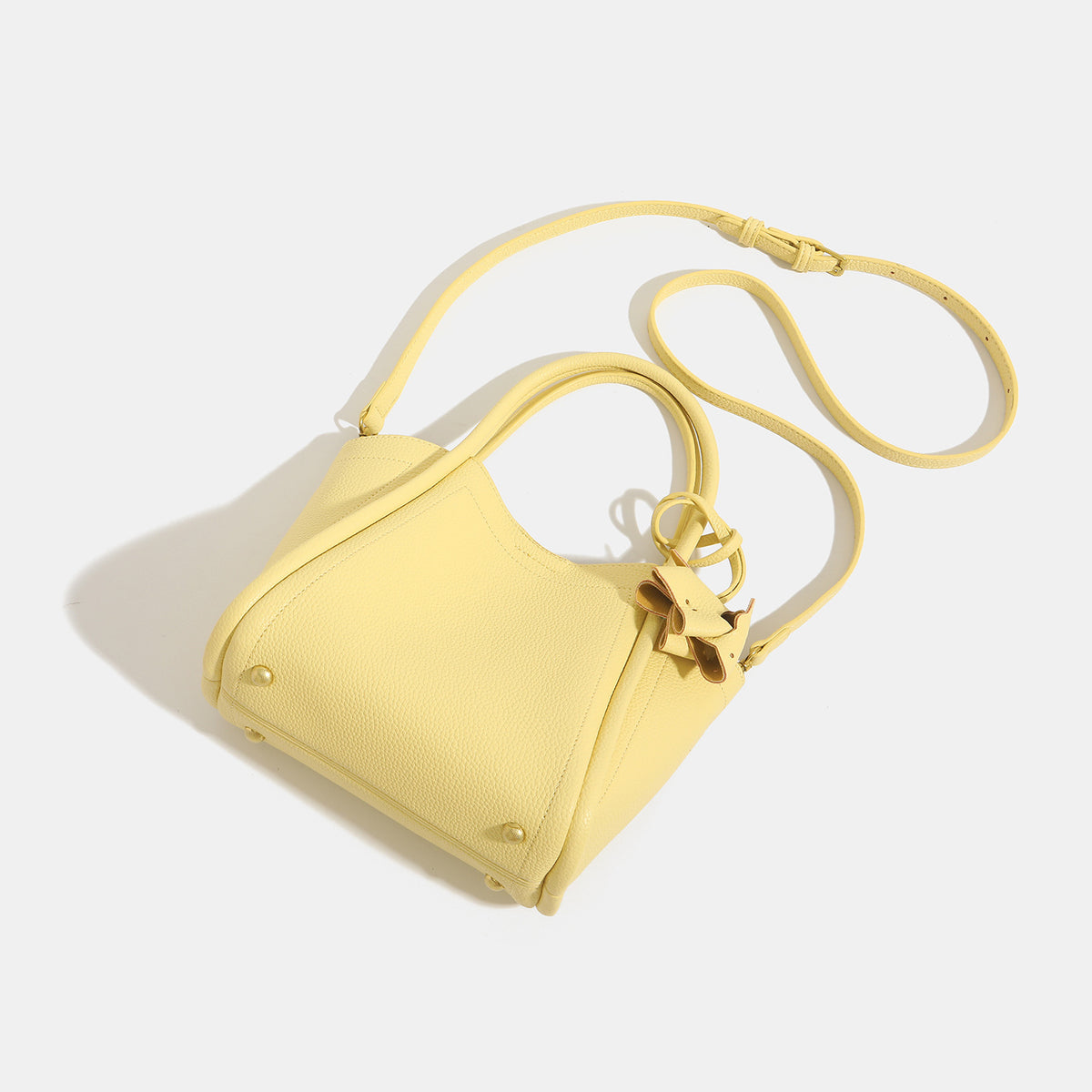Small structured pebbled leather-look bucket tote bag with bow charm tie closure and gold-tone hardware, detail view 4
