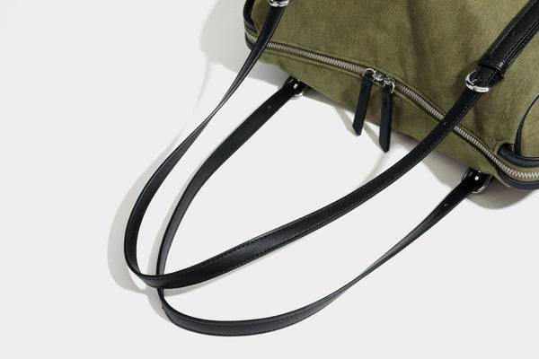 Olivgrüne Canvas-Schultertasche in Zylinderform mit schwarzen Trägern in Lederoptik, Reißverschluss oben und silberfarbenen Metallbeschlägen, Detailansicht