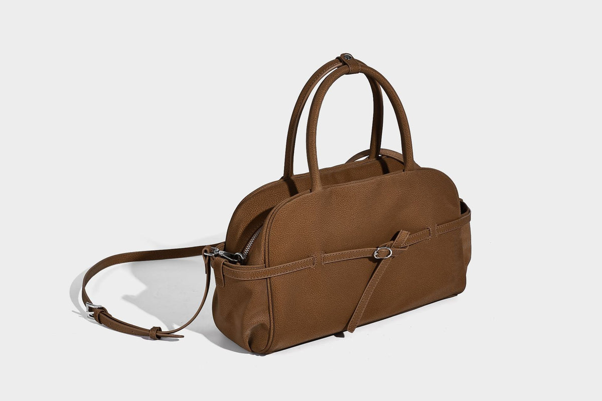 Strukturierte Henkeltasche aus mattem, genarbtem Material mit umlaufendem Riemen und Ringbeschlägen, zwei oberen Tragegriffen und abnehmbarem Crossbody-Riemen