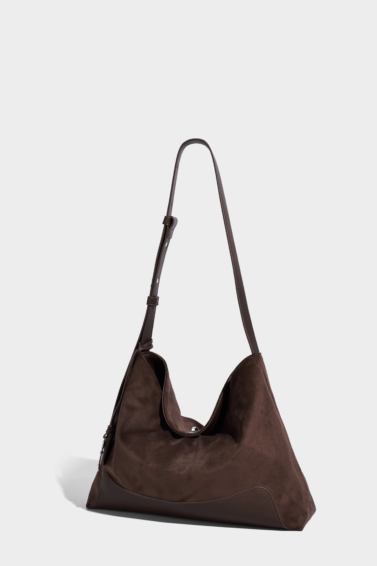 Dark brown slouchy hobo bag with matte suede-look body, smooth leather-look base trim, adjustable shoulder strap, and, detail