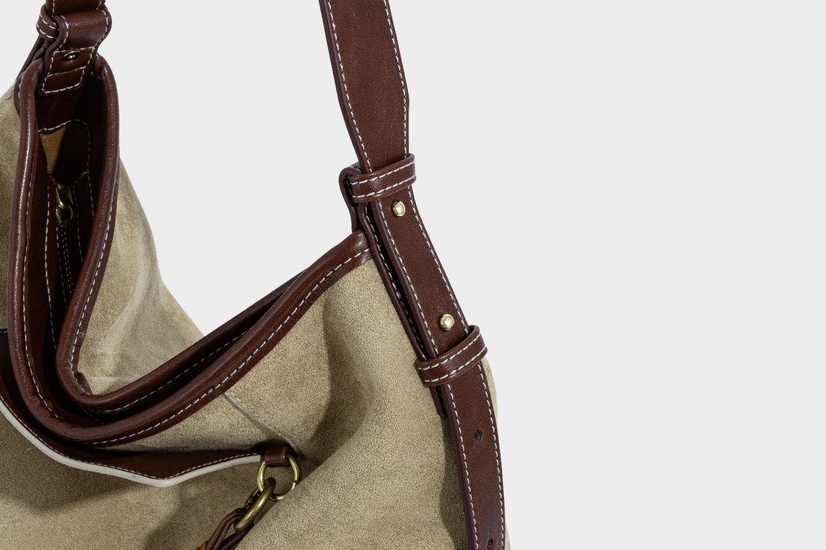 Lässig fallende Hobo-Schultertasche in Khaki aus mattem Material in Wildlederoptik mit dunkelbraunem Besatz in Lederoptik, Quastenanhänger mit Perlen und seitlicher Klappe, Detailansicht