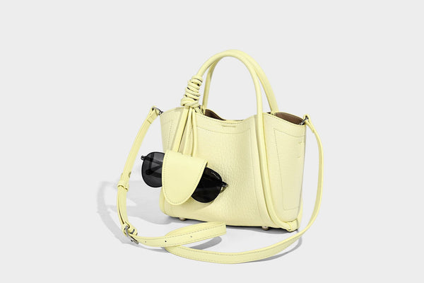 Structured mini tote bag in pebbled leather-look finish with knotted top handles, front flap pocket, and detachable shoulder