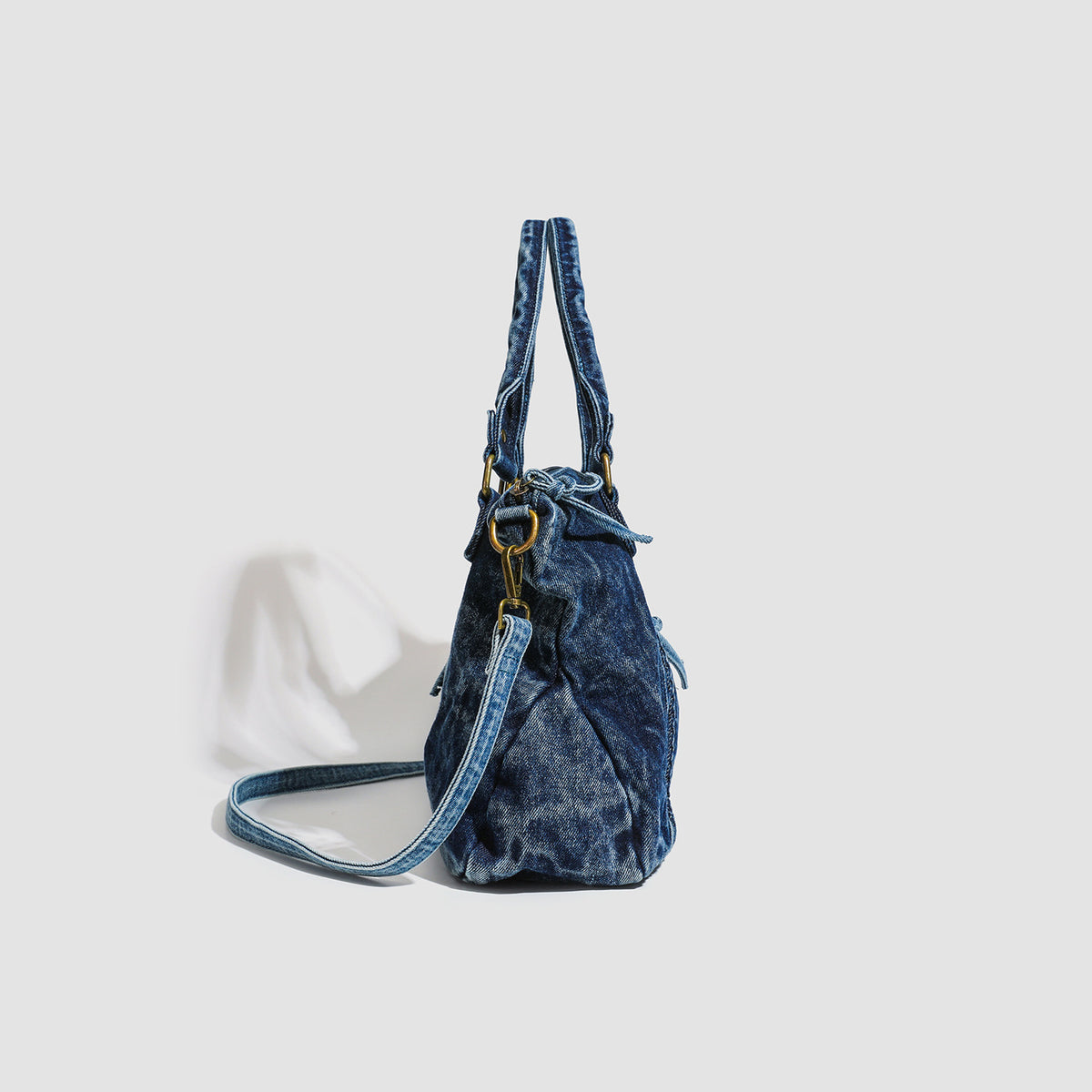 Large washed blue denim-look shoulder bag with gold-tone rings and rivets, top zip closure, front zip pocket, and adjustable