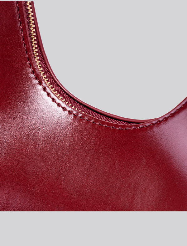 Glossy crescent hobo shoulder bag in deep burgundy with beaded wood tassel charm and gold-tone ring hardware, detail view 14