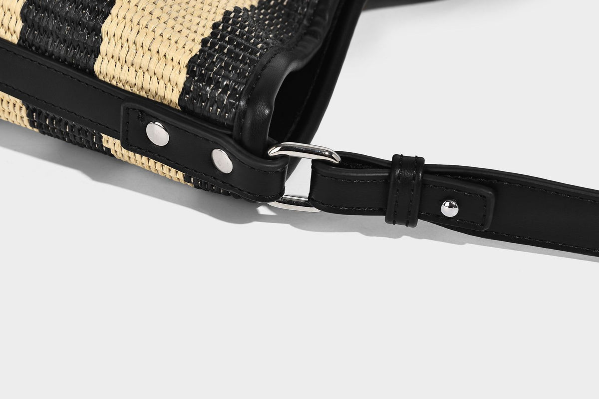 Gestreifte gewebte Bucket Bag in Schwarz und Beige mit schwarzem Besatz in Lederoptik, offener Oberseite und langem verstellbarem Schulterriemen, Detailansicht