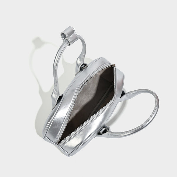Kompakte silberfarbene Mini-Boston-Tasche mit zwei Tragegriffen oben, silberfarbenen Metallelementen und abnehmbarem Crossbody-Riemen, Detailansicht